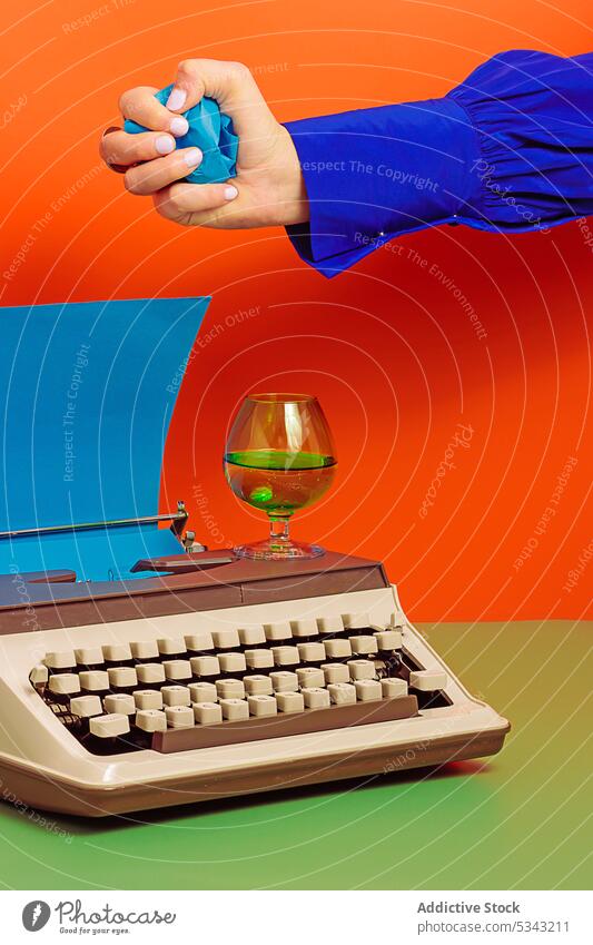 Frau mit Schreibmaschine legt zerknittertes Papier in einen Glasbecher farbenfroh zerknittern trinken altmodisch Farbblockierung Tasse retro Inspiration Stil
