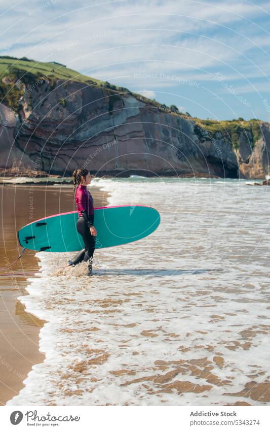 Junge Frau mit Surfbrett am Strand Surfer Meeresufer winken Aktivität Wasser Feiertag Sport Seeküste Urlaub Surfen MEER Sommer Küste Ufer Freizeit Hobby