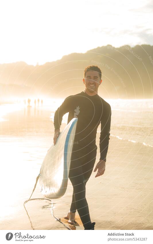 Mann geht mit Surfbrett am Strand spazieren Surfer MEER Sonnenuntergang winken Sport Meer Spaziergang Lächeln Wasser Sommer Hobby männlich Aktivität Abend Küste