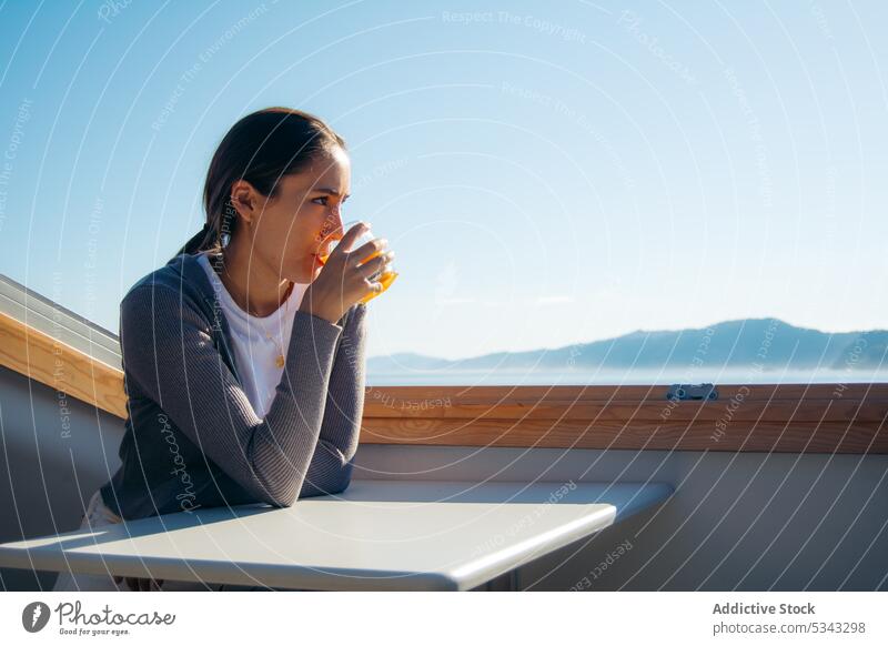 Nachdenkliche Frau trinkt frischen Orangensaft auf dem Balkon besinnlich trinken Windstille ruhen sich[Akk] entspannen bewundern Terrasse Getränk Saft lässig