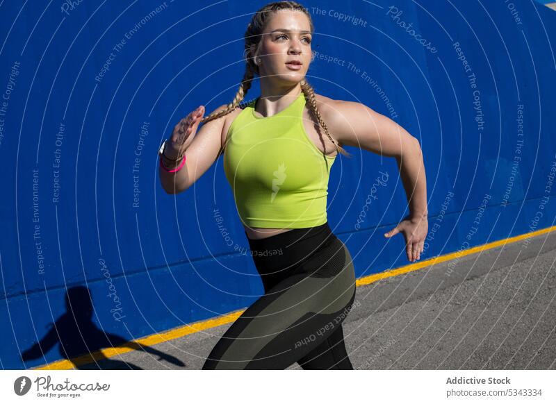 Starke Sportlerin beim Laufen und Trainieren in der Nähe der blauen Wand Frau Athlet Training Dehnung laufen Übung passen selbstbewusst Gesundheit Fitness jung