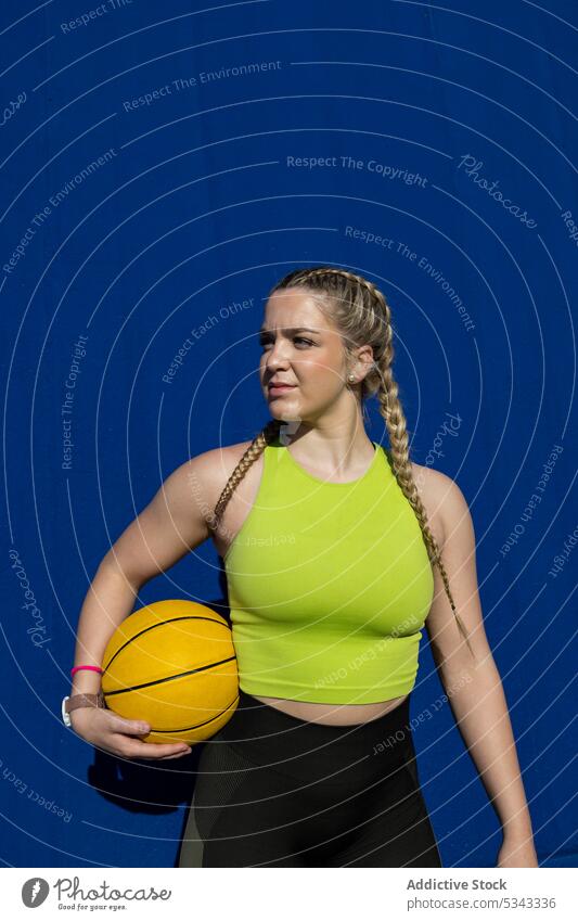 Sportlerin stehend mit Basketball auf blauer Wand Pause Ball selbstbewusst Athlet Training sich[Akk] entspannen Wellness Frau Korb Spieler Sportbekleidung jung