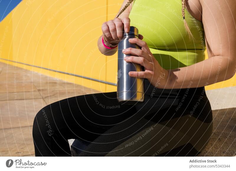 Anonyme Sportlerin mit Wasserflasche nach dem Training Frau Athlet Pause ruhen sich[Akk] entspannen Flasche Wand hell Sportbekleidung Beton Fitness passen