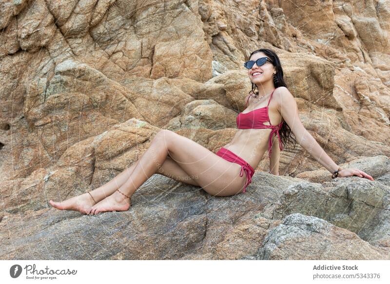 Lächelnde Frau im Bikini auf felsiger Klippe sitzend Felsen Reisender Glück Tourist Hügel heiter Urlaub Sommer Abenteuer Puerto Escondido Oaxaca Mexiko Feiertag