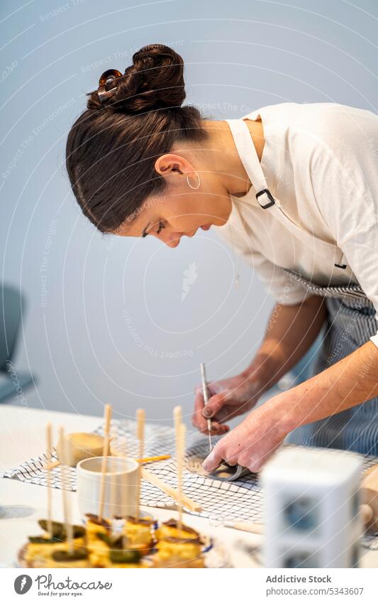 Frau zeichnet auf Ton am Tisch Töpferwaren machen Kunstgewerbler handgefertigt Werkstatt Keramik Arbeit zeichnen kreieren Werkzeug Fähigkeit Hobby Basteln