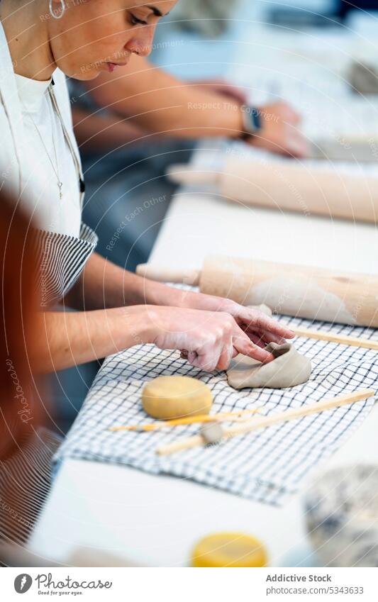 Crop Frau macht Loch in Ton auf dem Tisch Töpferwaren kreieren Kunstgewerbler Handwerk Steingut Werkstatt Tonwaren handgefertigt Fähigkeit Handwerkerin Hobby