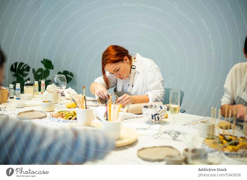 Konzentrierte Frau bei der Herstellung einer Tontasse während eines Töpferkurses Lektion Töpferwaren Tisch Tasse trinken Kunstgewerbler Handwerk handgefertigt