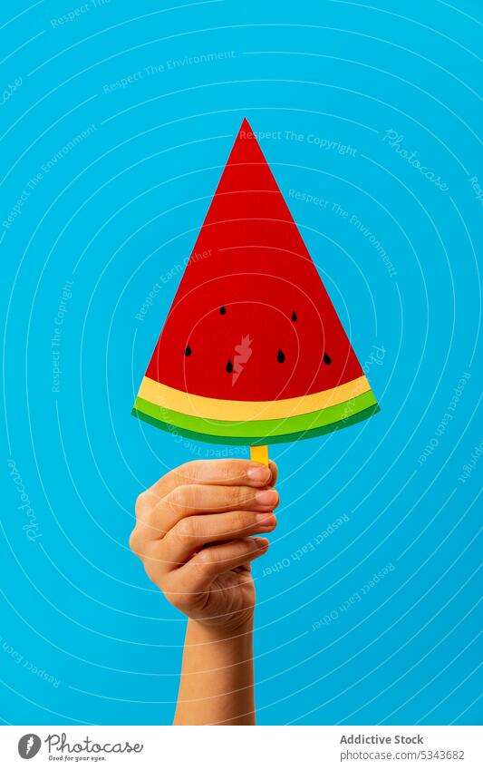 Crop anonyme Person zeigt Scheibe künstliche Wassermelone Stieleis manifestieren Frucht Sommer lecker süß kreativ Hand Kunst Papier hell zeigen frisch