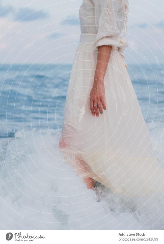 Anonyme Frau im Kleid geht im Meerwasser MEER Meeresufer Ufer Spaziergang Sommer Feiertag Strand Natur Urlaub winken Wasser Blauer Himmel Küste wolkig Harmonie
