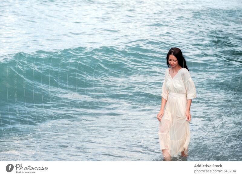 Ruhige Frau spaziert im wogenden Meer im Sommer MEER Urlaub Strand Wasser Kleid Meeresufer türkis charmant Spaziergang Natur Küste Feiertag jung reisen genießen
