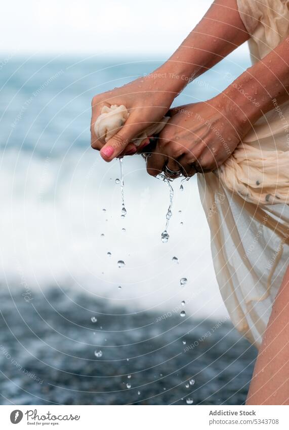 Crop-Frau, die ihr Kleid am Strand aus dem Wasser wringt MEER Ufer Küste Tourist ringen winken Sommer Natur Stein Reisender Ausflug Urlaub reisen Meer Resort