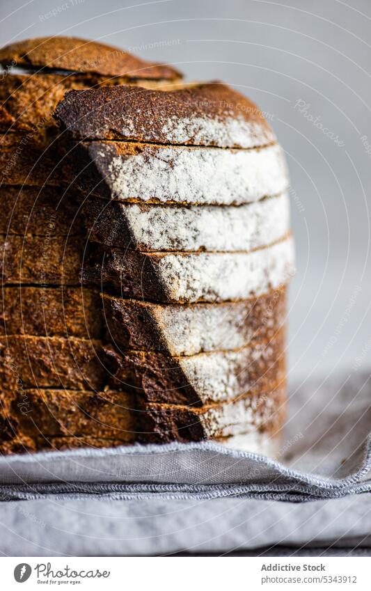 Vorderansicht eines Stapels von Roggenbrotscheiben auf einer grauen Stoffserviette vor einem unscharfen hellen Hintergrund Brot essen Essen Lebensmittel