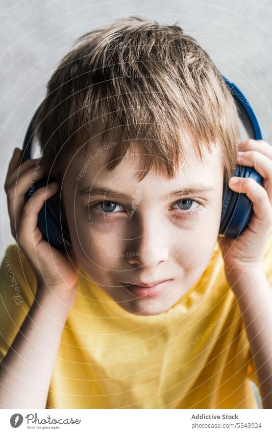 Vorderansicht eines niedlichen Kindes, das in die Kamera schaut, während es Musik hört schön Junge Ohr Auge Gesicht Kopfhörer menschlich zuhören über-Ohr Person
