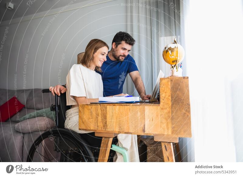 Junges Paar arbeitet zu Hause gemeinsam an einem Büroprojekt Laptop benutzend rollstuhl Reha deaktiviert Hilfsbereitschaft Glück Zusammensein Arbeit Projekt