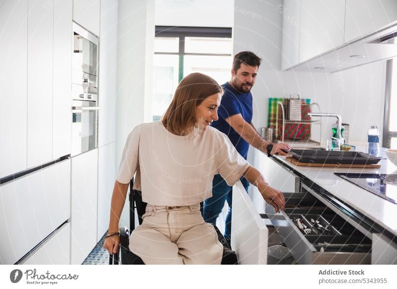 Positives junges Paar bereitet sich in der Küche auf das Kochen vor Familie Ehefrau Ehemann Reha deaktiviert Rollstuhl Glück Zusammensein Partnerschaft Bonden