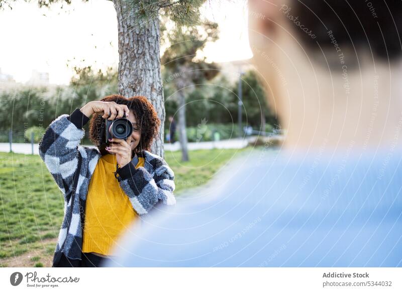 Junge Frau schießt Fotos in der Nähe von Bäumen auf grünem Gras fotografieren Fotoapparat Fotograf Park Baum Fotografie Hobby Fotokamera schießen professionell