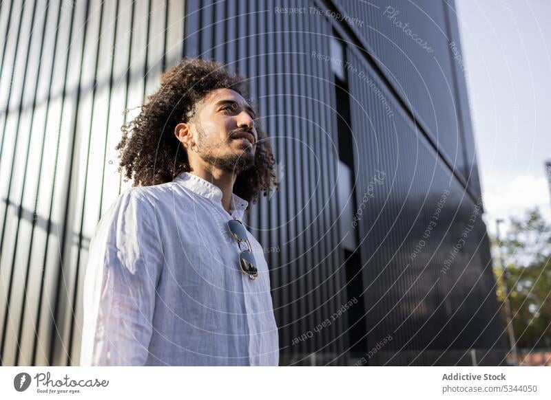 Glücklicher ethnischer Mann beim Spaziergang in der Stadt Straße selbstbewusst Großstadt besinnlich Afro-Look Apparatur männlich Afroamerikaner schwarz modern