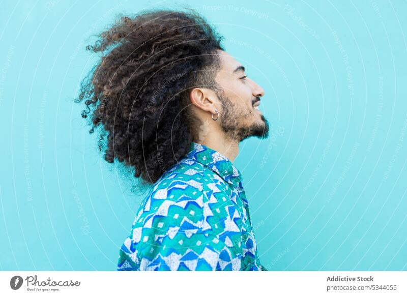 Seitenansicht eines fröhlichen schwarzen Mannes mit lockigem Haar krause Haare trendy Ohrringe Vollbart Afro-Look Stil Model Individualität Frisur ethnisch