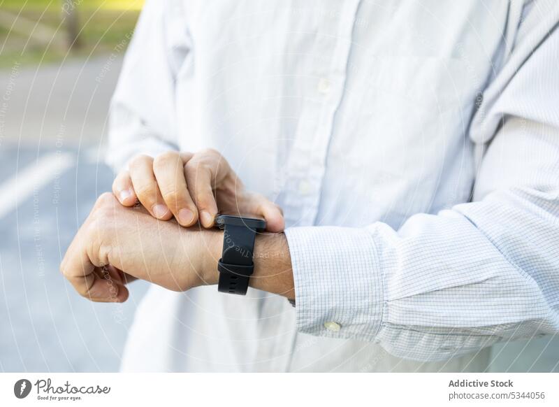 Crop-Mann mit Smartwatch auf der Straße intelligente Uhr prüfen Handgelenk Apparatur Gerät tragbar Armbanduhr klug modern urban Großstadt Lifestyle Zeit Tracker