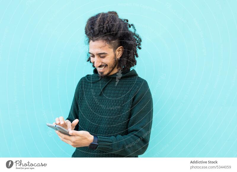 Fröhlicher schwarzer Mann mit Smartphone Nachricht Telefon Browsen Afroamerikaner ethnisch selbstbewusst Afro-Look Vorschein Outfit Funktelefon Apparatur cool