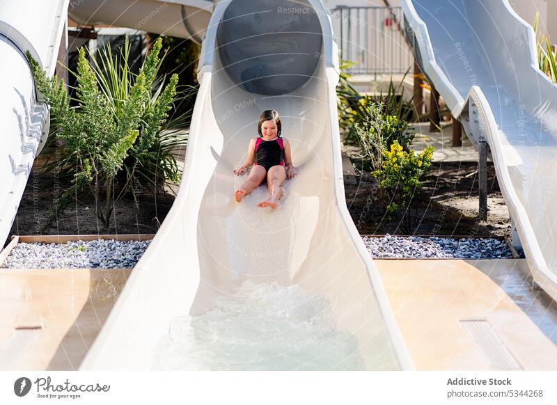 Lustiges Mädchen rutscht auf Wasserrutsche Sliden Resort Feiertag Pool ruhen Sommer Urlaub Wochenende tropisch Hotel Kind Aktivität Kindheit Spaß heiter Kälte