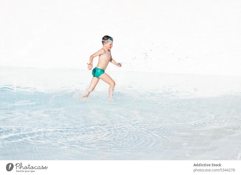 Fröhlicher Junge läuft im Schwimmbad mit Wasser schwimmen Pool Sommer Urlaub Resort laufen Feiertag platschen durchsichtig Kind ohne Hemd Beckenrand Erholung