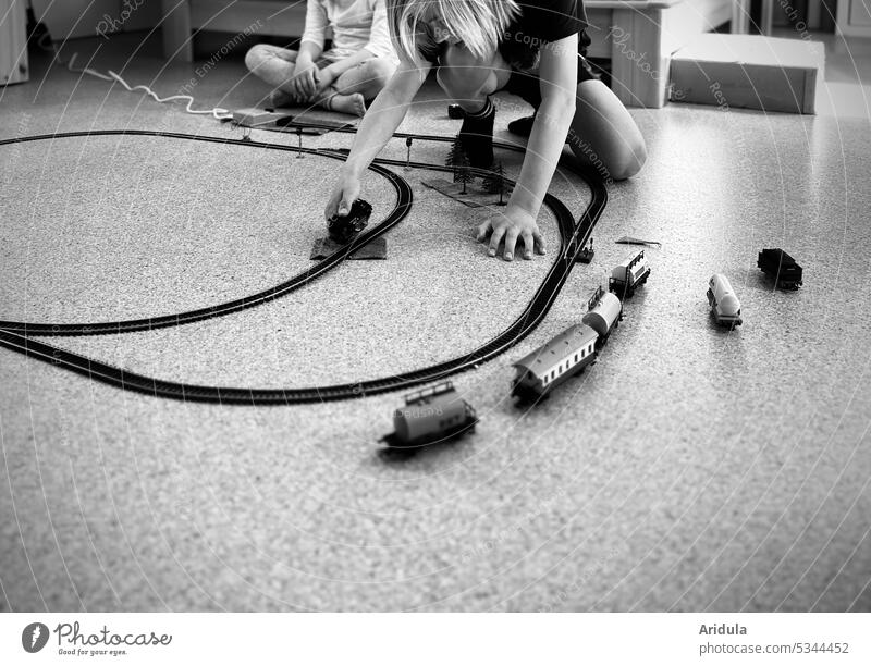 Kinder spielen mit Modelleisenbahn s/w Lok Wagon Spielzeug Schienen Kindheit Fußboden Bahn Zug Kindheitserinnerung