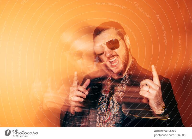 Zufriedener Mann mit Sonnenbrille im Studio nach oben zeigen Hipster aufgeregt trendy Stil gestikulieren Glück heiter männlich Vollbart Mund geöffnet erstaunt