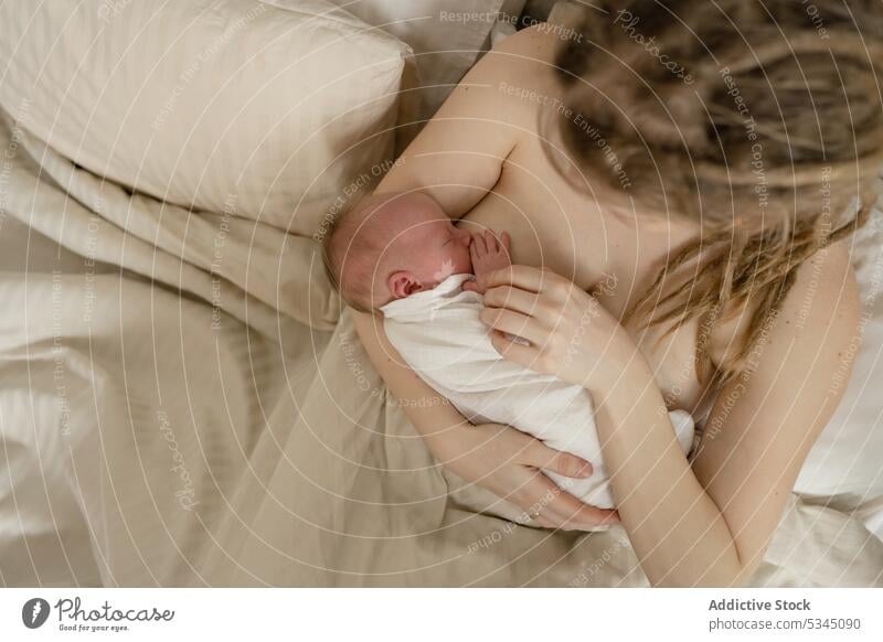 Mutter, die ihr Neugeborenes im Bett stillt Frau Baby Säugling stillen neugeboren Mama Kinderbetreuung mütterlich gemütlich Komfort unschuldig Mutterschaft