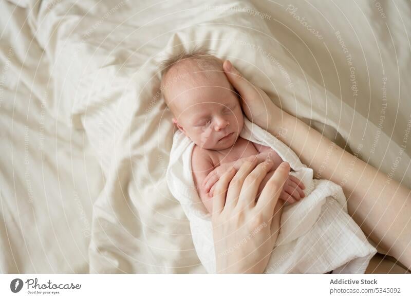 Anonyme Mutter streichelt Säugling auf weichem Bett Baby neugeboren schlafen Mama Kraulen Streicheln verwundbar Kind unschuldig Komfort gemütlich friedlich