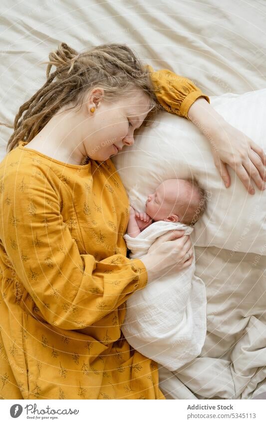 Frau mit Baby auf dem Bett liegend Mutter schlafen Säugling neugeboren Mama Komfort gemütlich Umarmung Kind unschuldig verwundbar friedlich Lügen schlafend