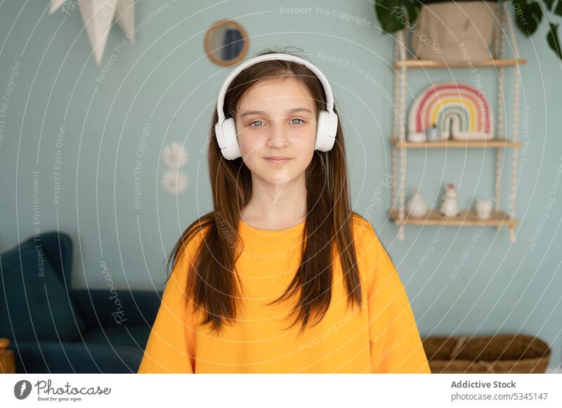 Nachdenkliches Kind mit Kopfhörern beim Musikhören Mädchen zuhören Porträt Schlafzimmer benutzend Apparatur nachdenklich modern ernst meloman Drahtlos