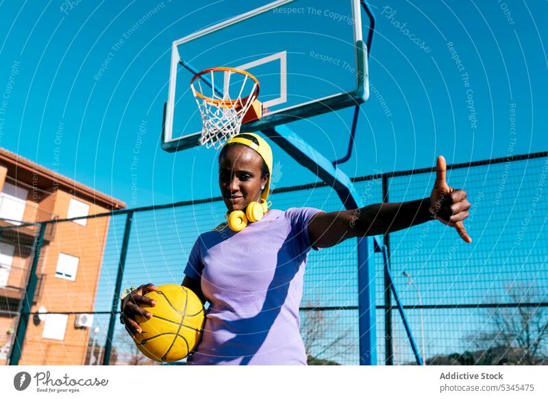 Schwarze Basketballspielerin mit Shaka-Zeichen auf einem Sportplatz im Freien Frau Spieler Sportpark gestikulieren selbstbewusst cool Athlet Ball Sportlerin
