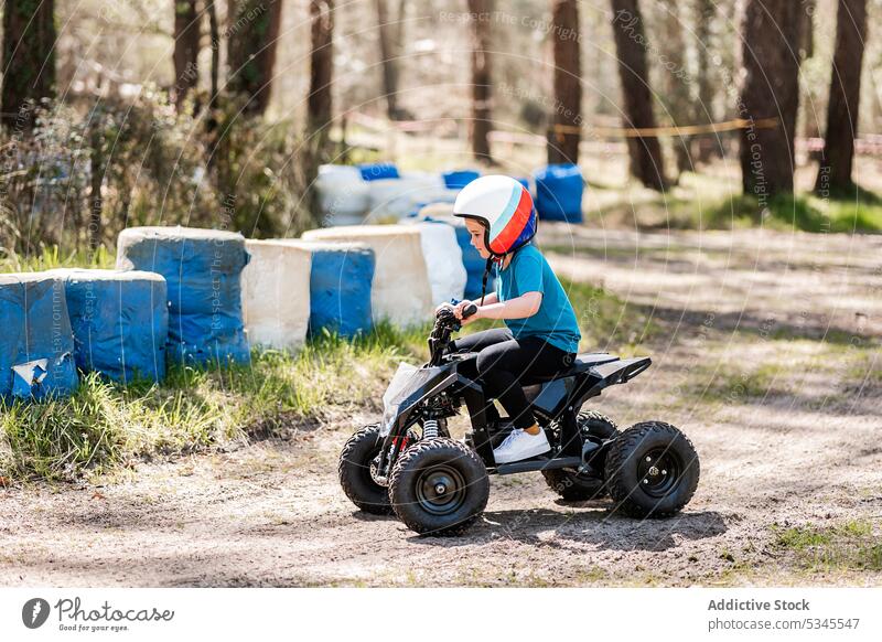 Ein Kind fährt mit einem Elektrofahrrad auf dem Lande Mädchen Motorrad Schutzhelm Mitfahrgelegenheit Vergnügen Aktivität Miete Park Landschaft Verkehr Natur
