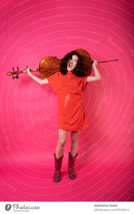 Stilvolle Frau mit Cello in rosa Studio trendy aufgeregt elegant akustisch farbenfroh Musiker Mode Instrument lebhaft hell Atelier Studioaufnahme Klang Talent