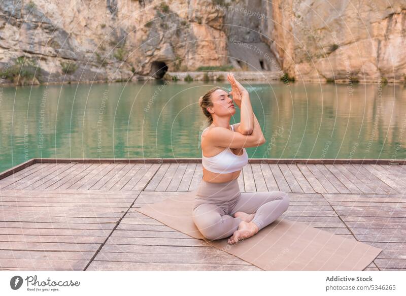 Fit Frau übt Yoga auf Pier Windstille üben Zen Gesundheit Asana Harmonie Wellness meditieren See Berge u. Gebirge Pose Adler-Pose garudasana Lifestyle