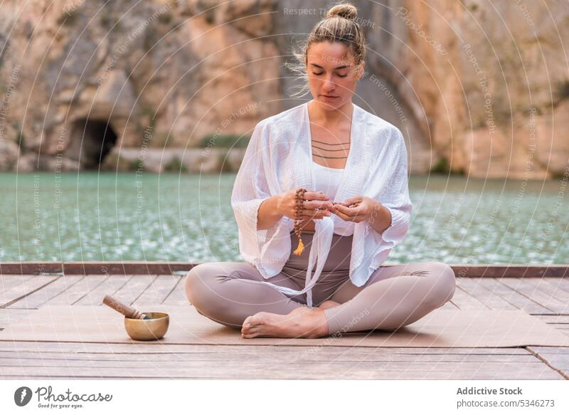 Frau übt Yoga in der Nähe eines Bergsees meditieren Klangschale Pier Charco Azul Stressabbau Valencia Spanien Konzentration Zen üben Wellness Sprit