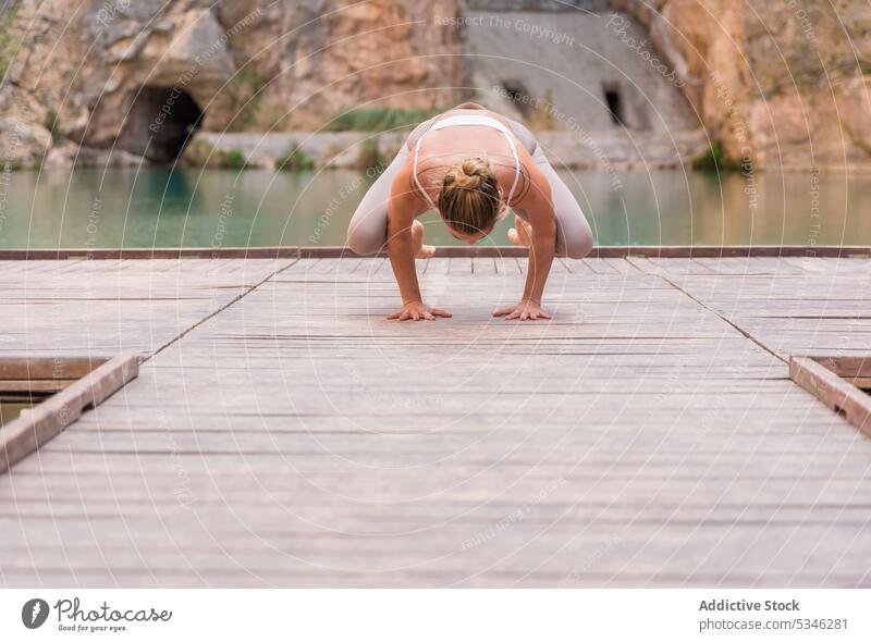 Flexible Frau in Kranich-Pose passen beweglich Yoga üben Asana Kranichpose Gleichgewicht Charco Azul Spanien Wellness Harmonie See Berge u. Gebirge Natur