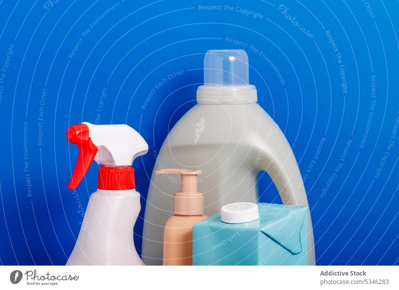 Generative AI-Illustration von verschiedenen Reinigungsmitteln in Kunststoff-Flaschen und Spendern auf blauem Hintergrund, die das Konzept der Recycling-Verpackung
