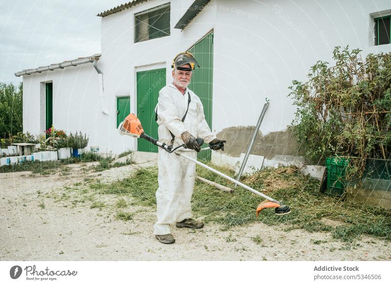 Anonymer älterer Mann, der Gras mit einem Freischneider schneidet Landwirt geschnitten Garten Landschaft Arbeit vorbereiten Sommer männlich gealtert Senior