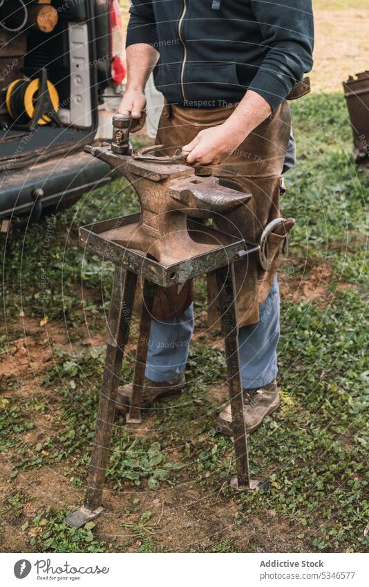 Unbekannter Hufschmied befestigt Hufeisen auf dem Amboss Mann Hammer schmieden Gerät Instrument Reparatur Landschaft Arbeit Uniform professionell manuell