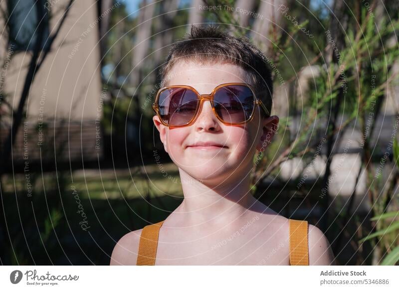 Stilvoller Junge mit Sonnenbrille in der Nähe von Pflanzen stehend Natur Sommer Urlaub Glück selbstbewusst Kind Garten Brille Augen geschlossen nackter Torso
