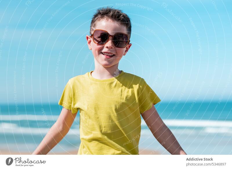 Junge mit ausgestreckten Armen genießt den Wind am Strand MEER Wasser Freiheit Blauer Himmel Kind Urlaub Glück Sonne ausdehnen froh Kindheit genießen positiv