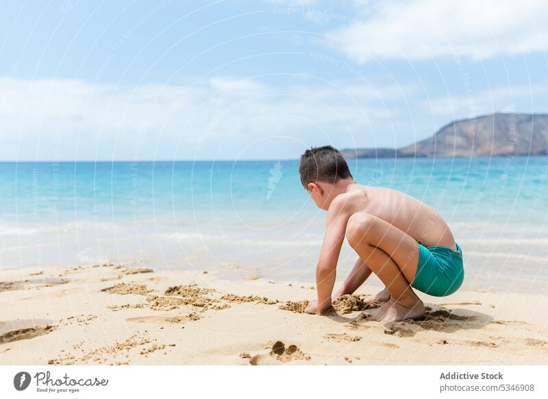Unbekannter Junge in Shorts spielt mit Sand Strand MEER Kind Ufer Aktivität Saison sorgenfrei Vergnügen Seeküste Resort Wasser Küste sich[Akk] entspannen
