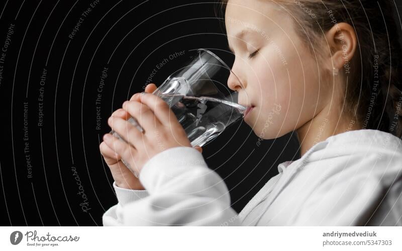 Wasserhaushalt und Gesundheitsvorsorge für Kinder. Kleines Mädchen trinkt frisches transparentes reines gefiltertes Mineralwasser zu Hause. Durstig dehydriert Teenager hält Glas Hydrating Durst am Morgen gesund zu sein