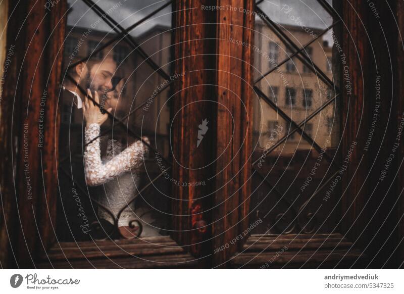 Junge stilvolle Jungvermählte umarmen sich hinter einer alten rustikalen Holztür. Hochzeitstag. Paar stylisch jung lviv Architektur Hintergrund schön Reichtum