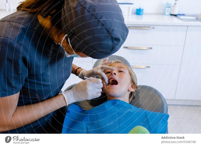 Anonymer Zahnarzt, der die Zähne eines Patienten behandelt Frau geduldig untersuchen Medizin Kind Uniform Arzt Mundschutz Gesundheitswesen Werkzeug Arbeit