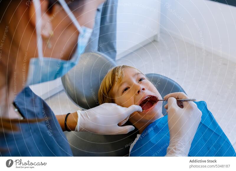 Anonymer Zahnarzt, der die Zähne eines Patienten behandelt Frau geduldig untersuchen Medizin Kind Uniform Arzt Mundschutz Gesundheitswesen Werkzeug Arbeit