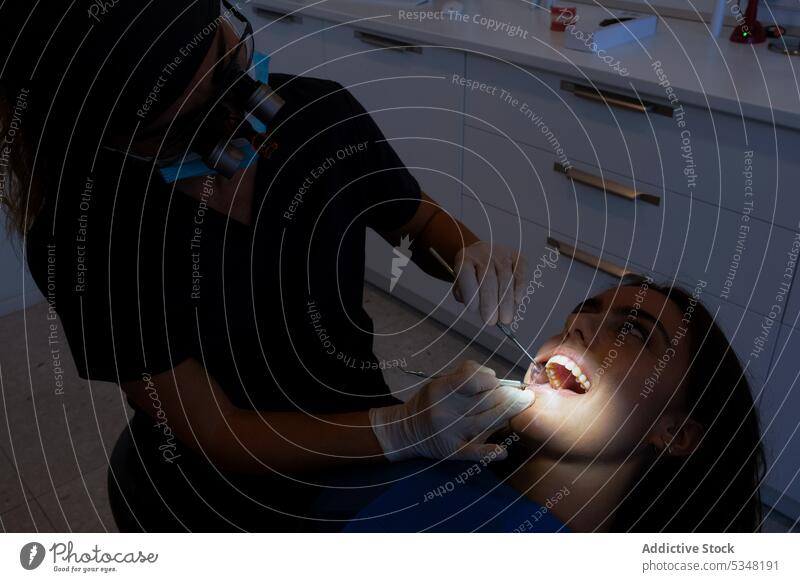 Zahnärztin mit Mikroskopbrille bei der Untersuchung der Zähne eines Patienten Zahnarzt untersuchen geduldig Frau Werkzeug Klinik Zahnmedizin professionell Gerät