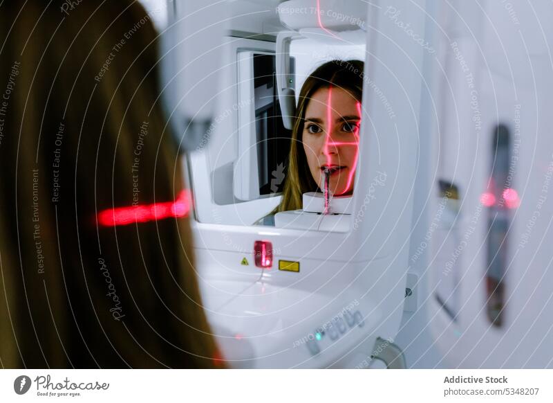 Junge Frau in zahnärztlichem Röntgen-Digitalscanner in heller Klinik lässig Röntgenbild Maschine dental digital Stomatologie Scanner Gerät Zahnmedizin benutzend